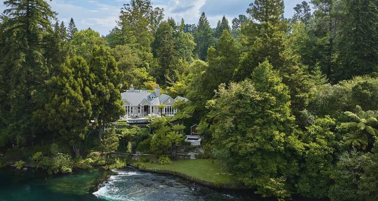 Vue aérienne d'une maison entourée d'une végétation luxuriante et d'une rivière.