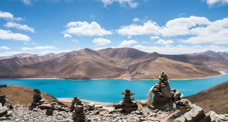 Un lac serein dans les montagnes avec des cairns de pierre au premier plan.