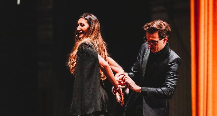 Two people performing a magic trick on stage.