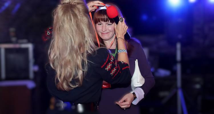 Person placing a red clown nose on another person.