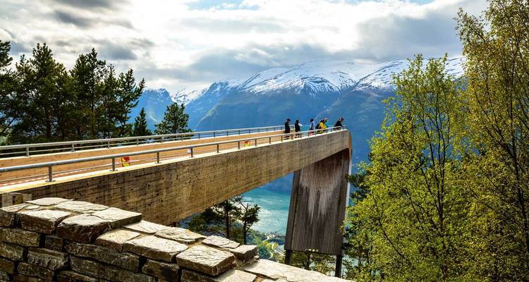 Plateforme d'observation surplombant un fjord avec des montagnes enneigées.