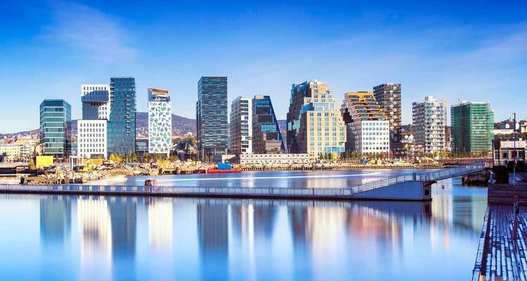 Paysage urbain de bâtiments modernes au bord de l'eau sous un ciel bleu dégagé.