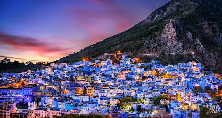 Paysage urbain de Chefchaouen au crépuscule avec des bâtiments bleus.