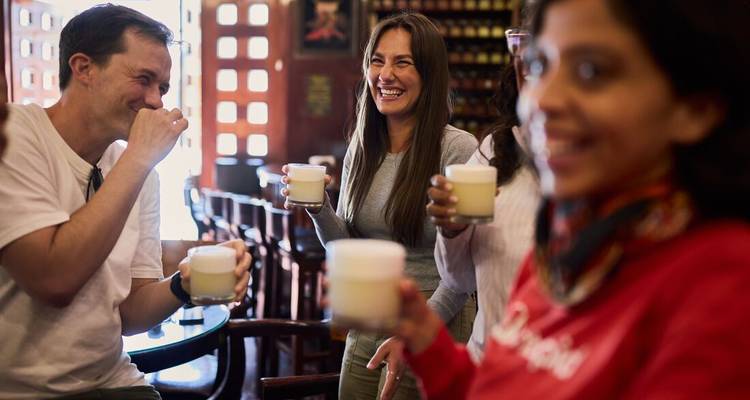 Group of people enjoying drinks and laughing in a cozy setting.