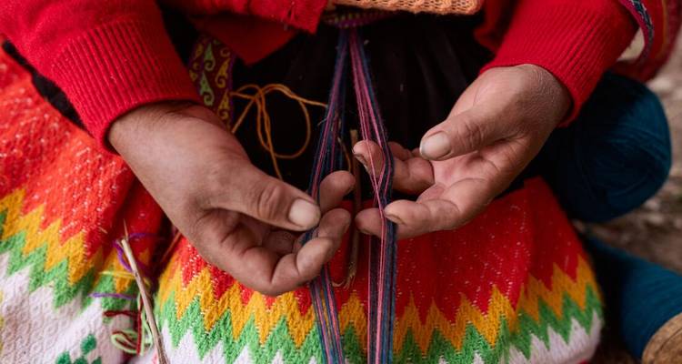 Hands weaving colorful yarn in a traditional pattern.