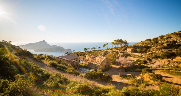 Une colline pittoresque avec des bâtiments et une vue sur la mer sous un ciel clair.