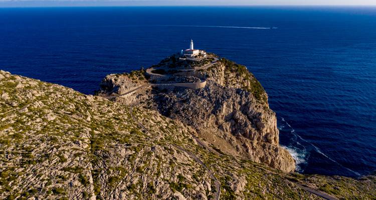 Une vue aérienne d'un phare sur une falaise rocheuse entourée par l'océan.