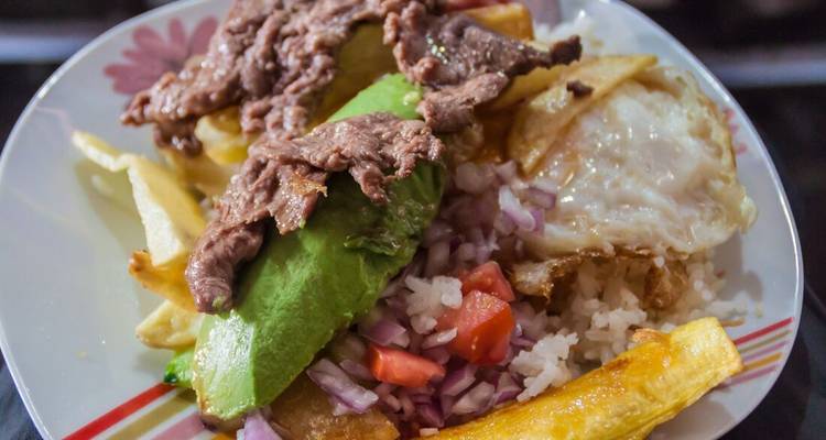 Une assiette de nourriture péruvienne avec avocat, œuf frit et riz.