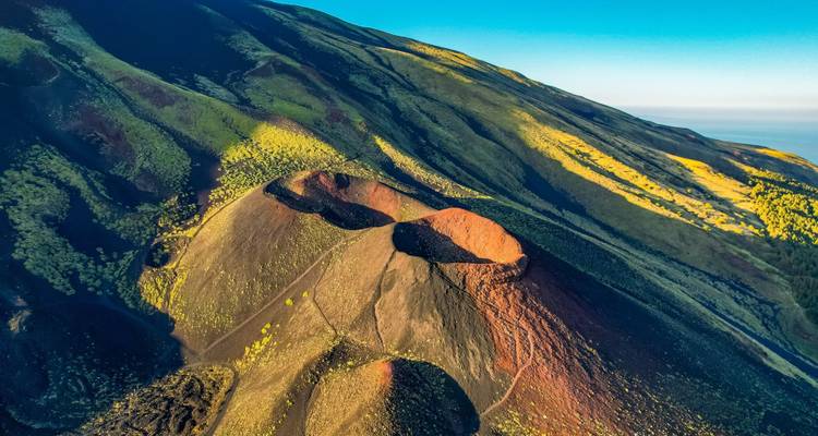 Luchtfoto van vulkanisch landschap met kleurrijke kraters en omliggende terrein.