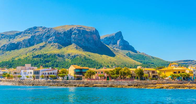 Village côtier avec des bâtiments colorés et des montagnes.