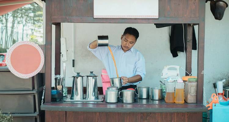 A person preparing a drink at a small beverage stand.