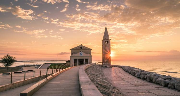 Église au bord de la côte au coucher du soleil, avec des couleurs de ciel éclatantes.