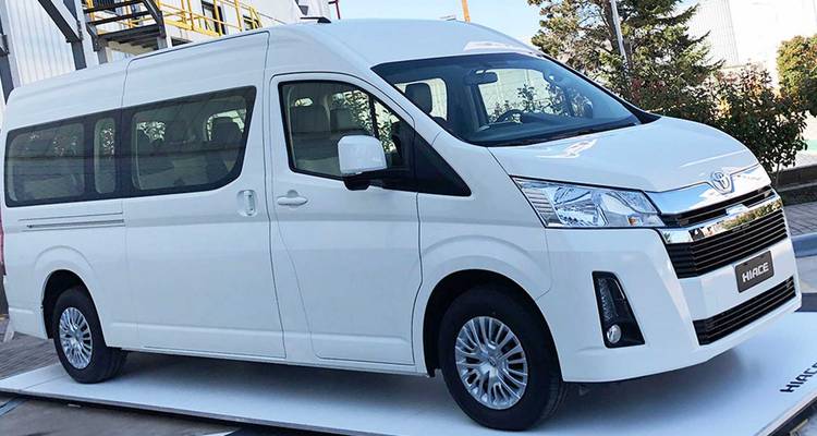 Minibus blanc exposé sur une plateforme dans un environnement industriel.