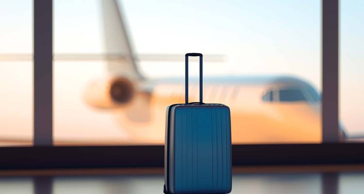 Une valise devant un avion dans un aéroport.