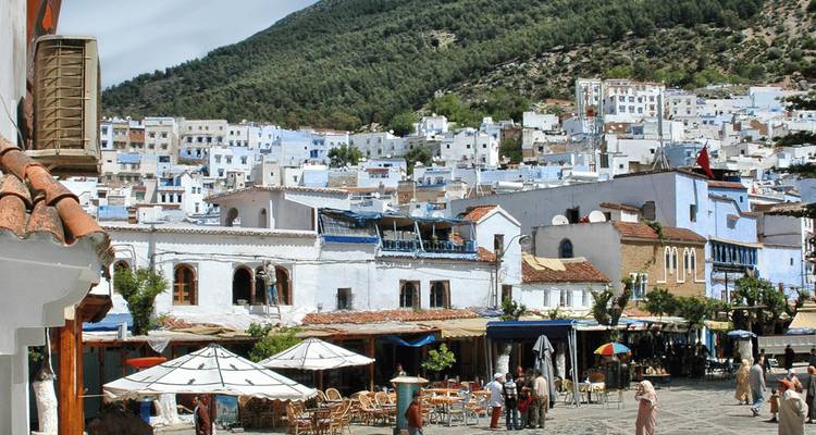 Traditional Moroccan blue town with people and shops.