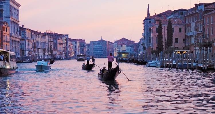 Gondolas navigating a canal in Venice with historic buildings lining the waterway.