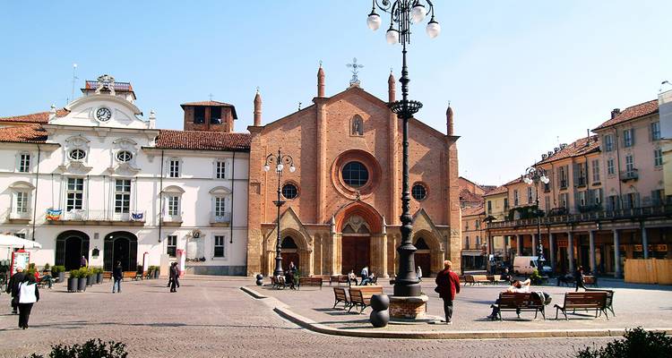 Place historique avec une grande église et des gens qui marchent.