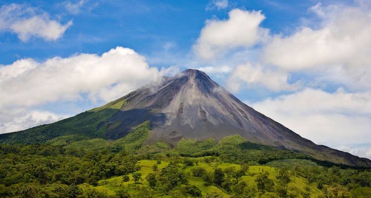 Volcan Arenal entouré d'une forêt luxuriante sous un ciel dégagé.