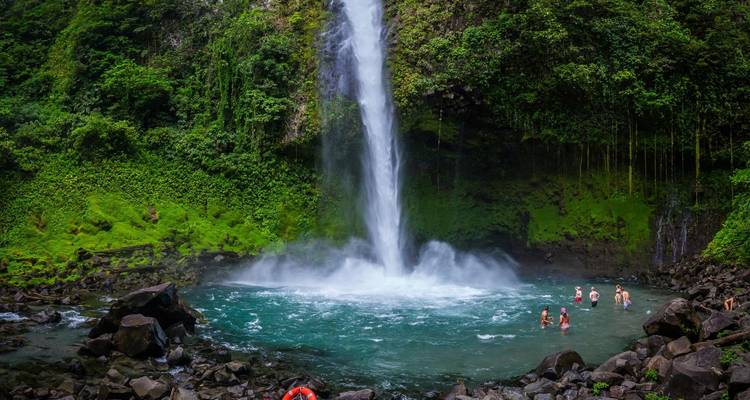 Cascade coulant dans un bassin avec des gens qui nagent en dessous.