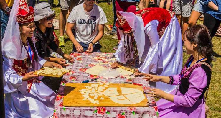 People in traditional costumes preparing food at a festival.