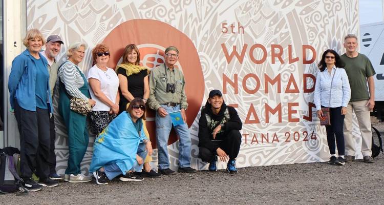Grupo de turistas parados frente al banner de los 5tos Juegos Mundiales Nómadas.