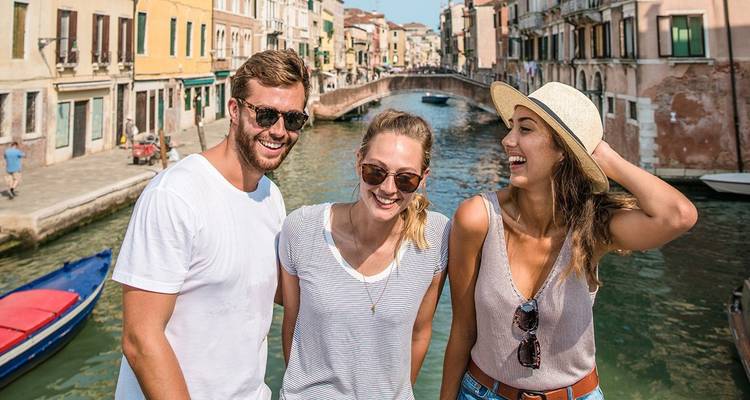 Three people smiling in front of a Venetian canal.