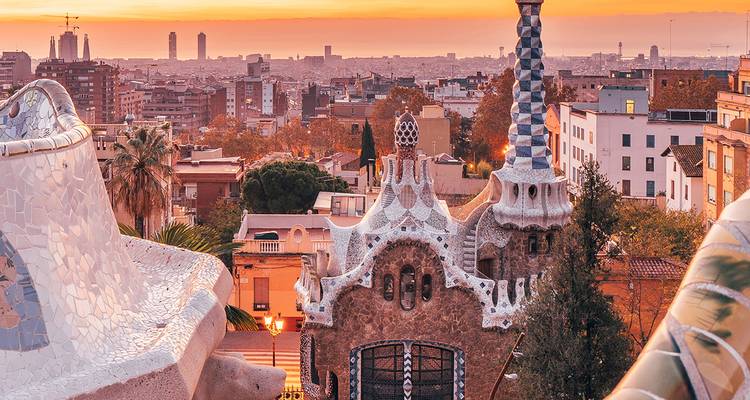 Iconic mosaic terraces of Park Güell frame a sunrise view over Barcelona's cityscape