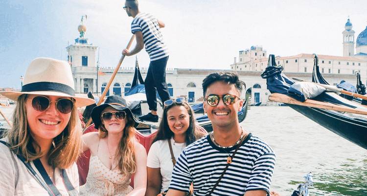 Des voyageurs souriants profitent d'une promenade en gondole sur la lagune avec l'horizon historique de Venise en arrière-plan