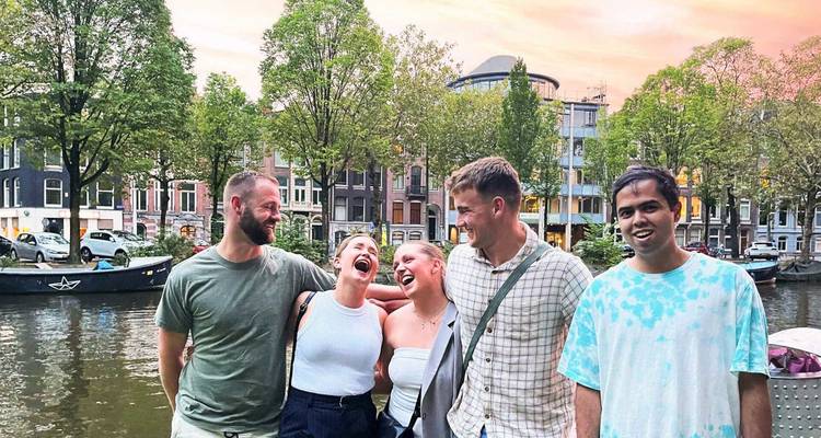 Groep vrienden lachend bij een kanaal met bomen.