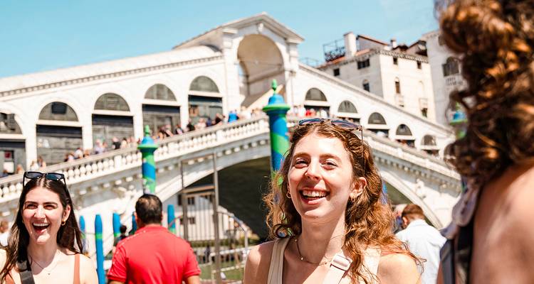De jeunes voyageurs rient près du pont du Rialto à Venise par une journée ensoleillée