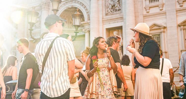 Crowd gathered near a famous fountain with sunlight filtering through.