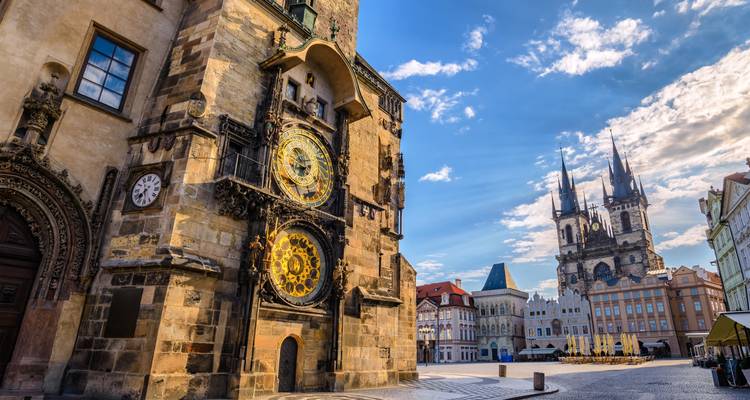 Torre del reloj histórica y una iglesia en una plaza de ciudad europea.