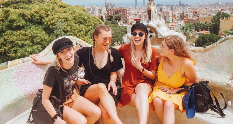 Quatre amis assis sur un banc en mosaïque colorée avec vue sur une ville.