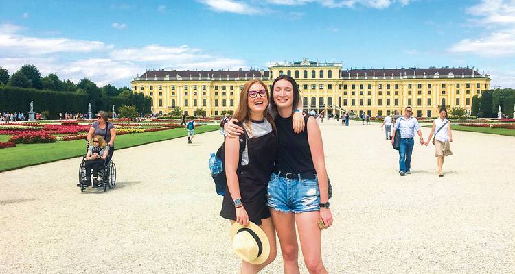 Two friends posing in front of an expansive, historic palace.