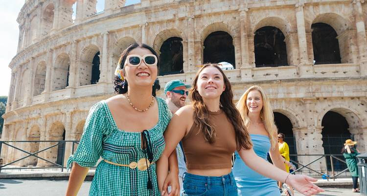 Vrolijke vrienden verkennen buiten het Colosseum van Rome onder een heldere blauwe hemel
