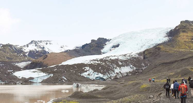 Wandelgroep nadert een uitgestrekte gletsjer te midden van ruige IJslandse bergen en een smeltwater lagune