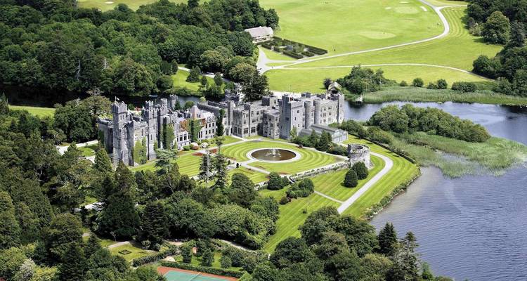 Aerial view of a large historic castle surrounded by lush greenery.