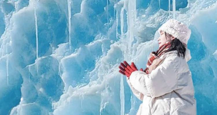 Person dressed in winter clothing standing in front of an ice formation.