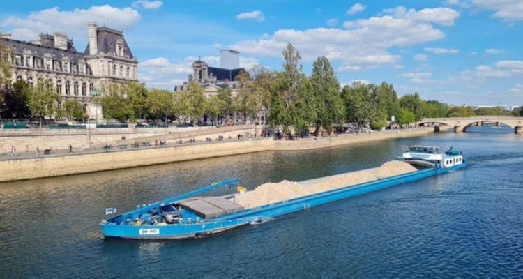 A barge on a river passing by historic buildings.