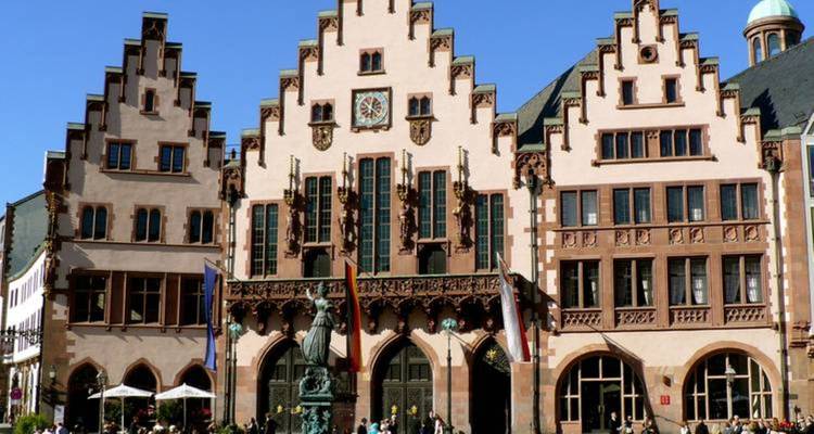 Historical building with stepped gables and a statue in front.