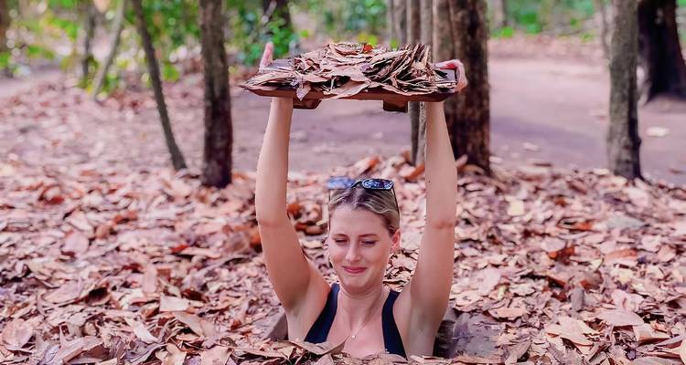 Woman emerging from a leaf-covered tunnel in the forest.