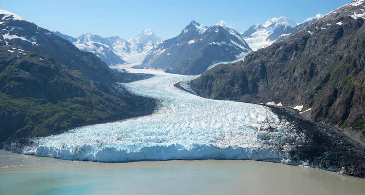 Massive glacier flowing through rugged mountain landscape.