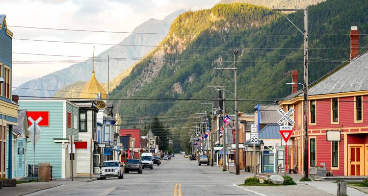 Small town street with colorful buildings and mountain backdrop.