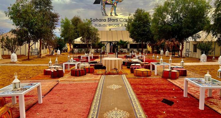 Configuration de repas en plein air avec tapis colorés et coussins.