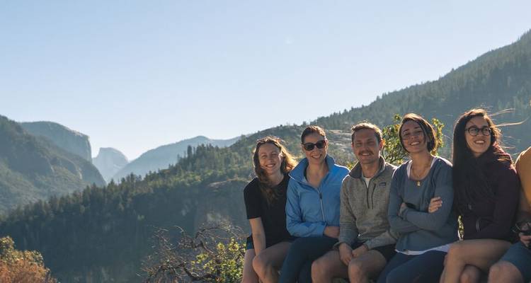 Group posing in front of forested mountains.