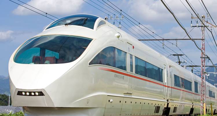 White bullet train traveling through rural Japan landscape.