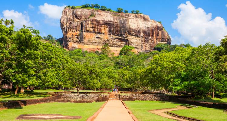 La forteresse rocheuse de Sigiriya dominant des terres verdoyantes sous un ciel bleu clair.