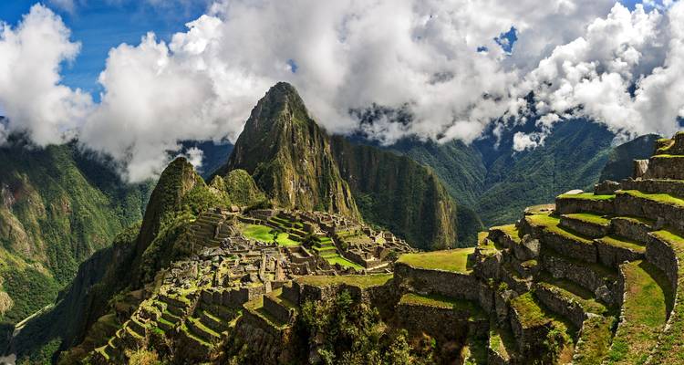 Iconisch panoramisch uitzicht op Machu Picchu ruïnes gelegen op bergkammen onder dramatische wolken