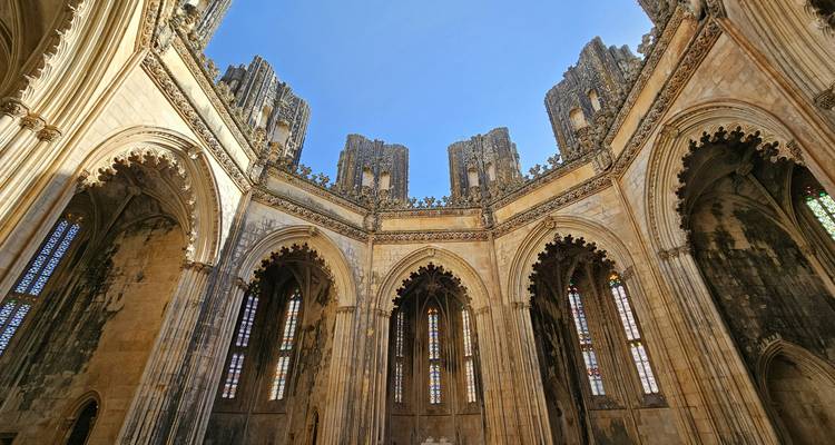 De hoog oprijzende openlucht kerkschip van het klooster van Batalha toont ingewikkelde gotische bogen tegen een diepblauwe hemel.