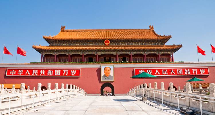 Iconische Tiananmenpoort met Mao-portret, rode muren en vlaggen onder heldere blauwe Peking-hemel